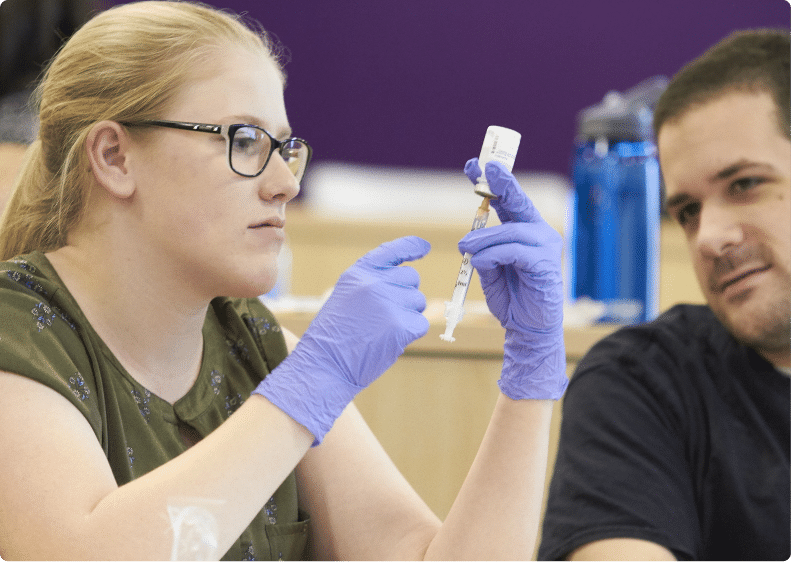 young woman and young man look at a syringe in a lab