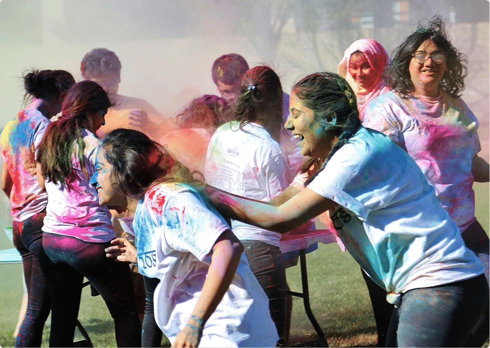 Students celebrating Holi with colorful paint powder.