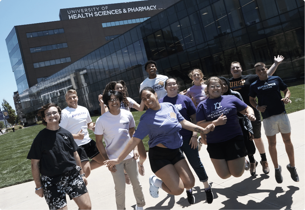 group of students jumping in front of the UHSP building