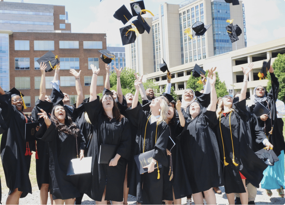 Recent graduates throw their caps in the air on the UHSP Quad during graduation