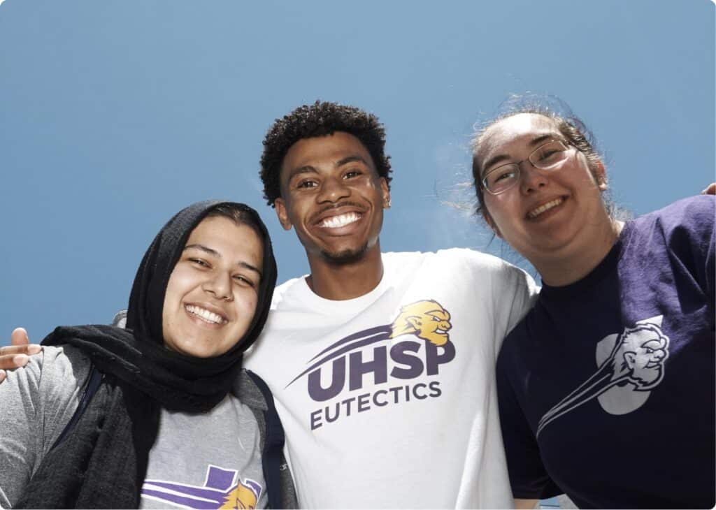 Group of three students smiling at camera