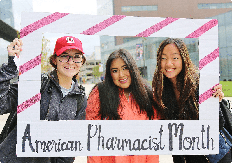 three students smiling and posing in a frame for American Pharmacist Month