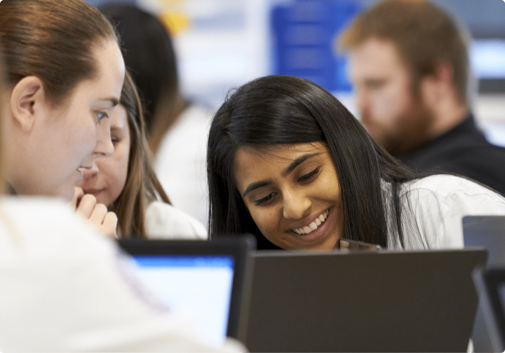 students smile while working on laptop