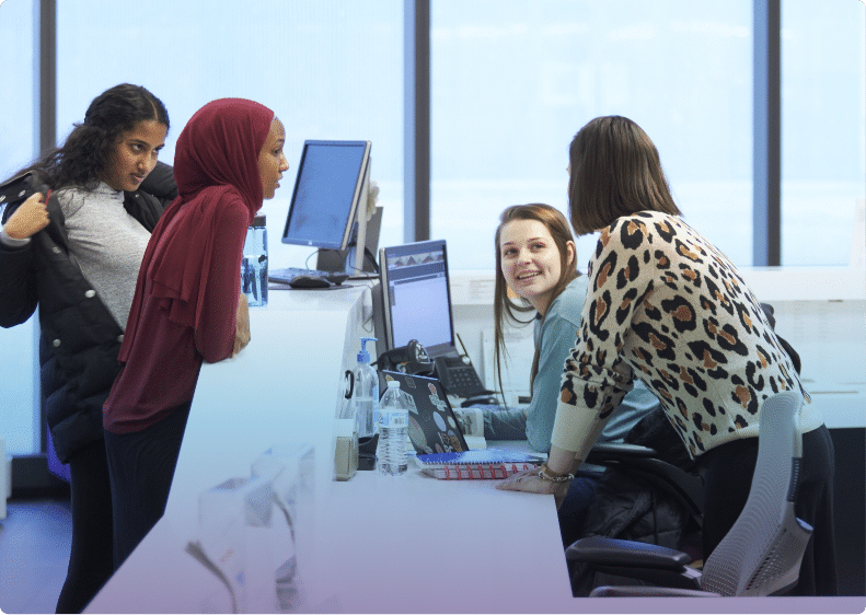 Students surrounding computer screen, smiling and laughing