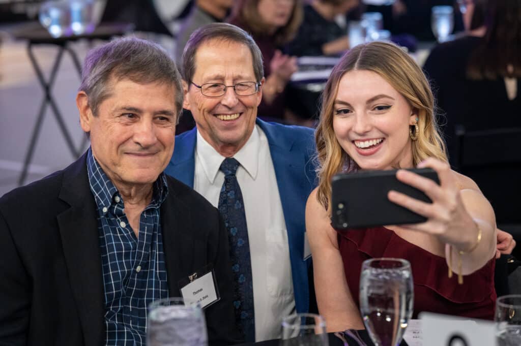 trio of two alumni and a student take a selfie during an alumni networking event