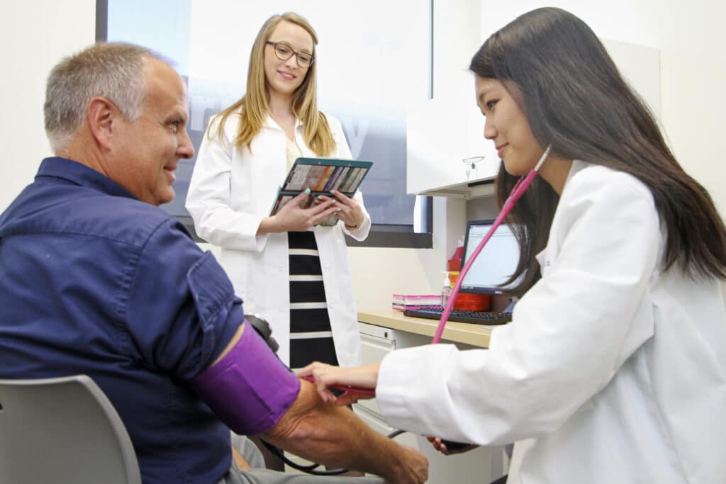 Pre-osteopathic medicine student practices taking patient's blood pressure