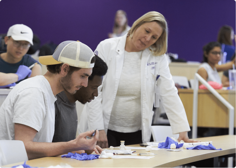 Female professor mentoring two male students in classroom