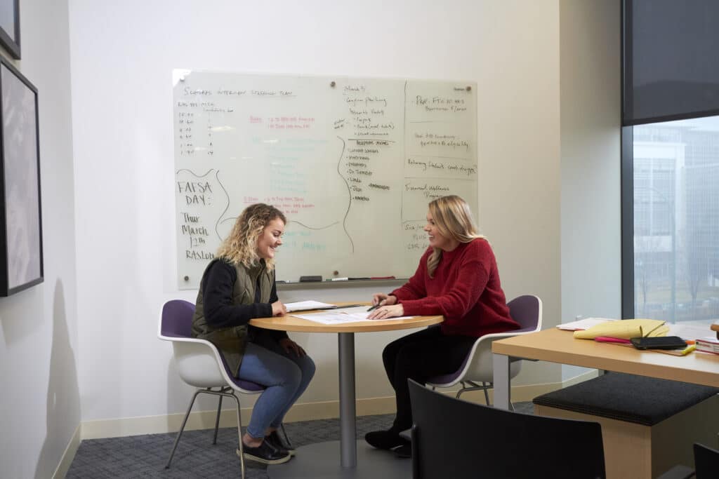 two women sitting at a table in an office