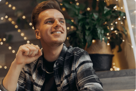 Man smiling surrounded by twinkle lights