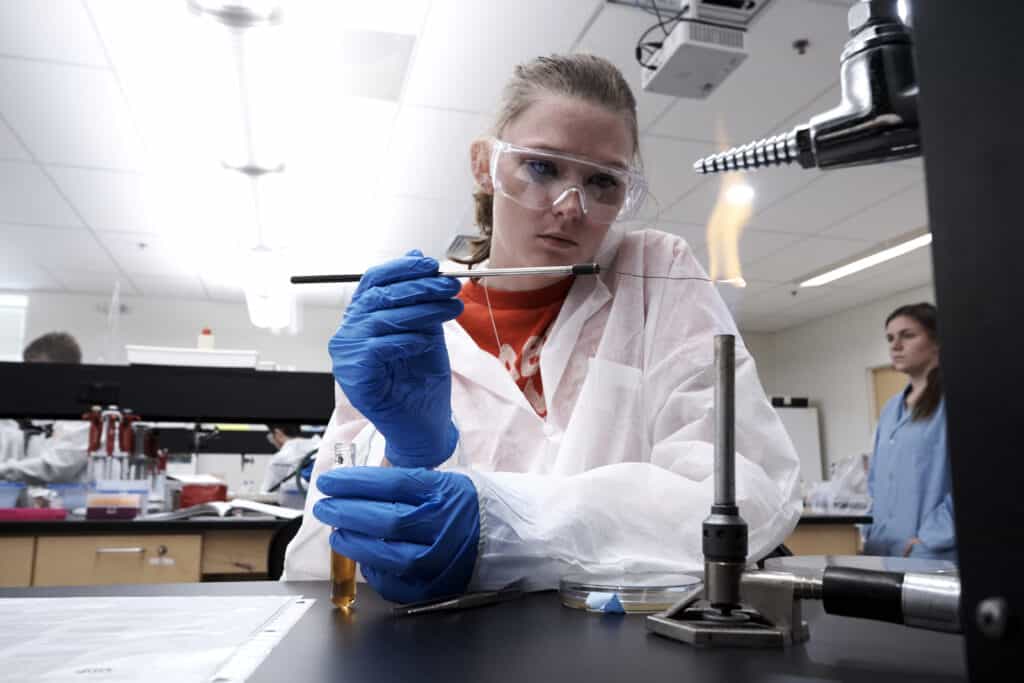 Student conducts experiment over open flame in the lab.