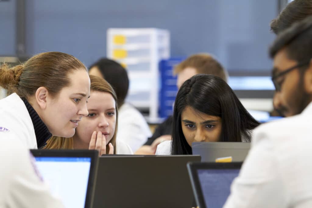 Group of students huddle close to collaborate on computer