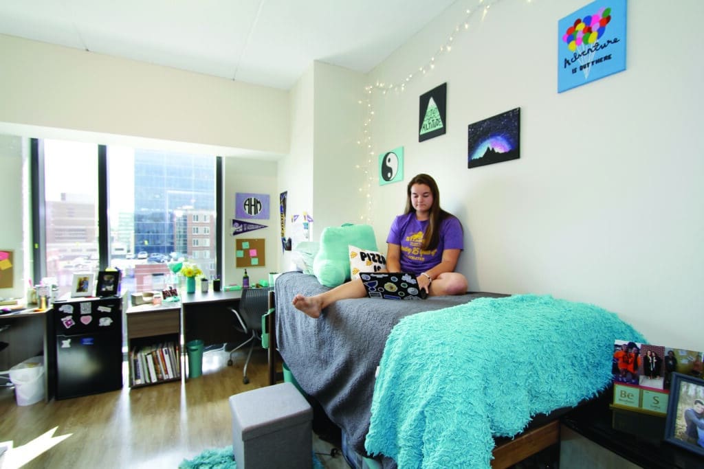 female student studies on her dorm room bed