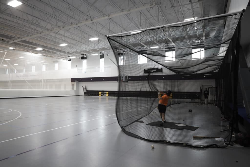 Baseball player practices hitting in the recreation gym