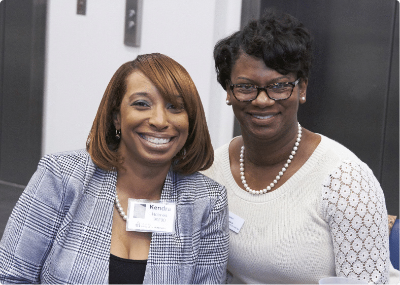 Two alumnae smile to camera during a UHSP alumni event.