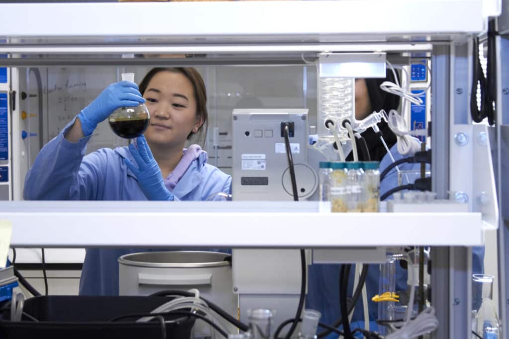 A student holds a round-bottomed flask in a lab