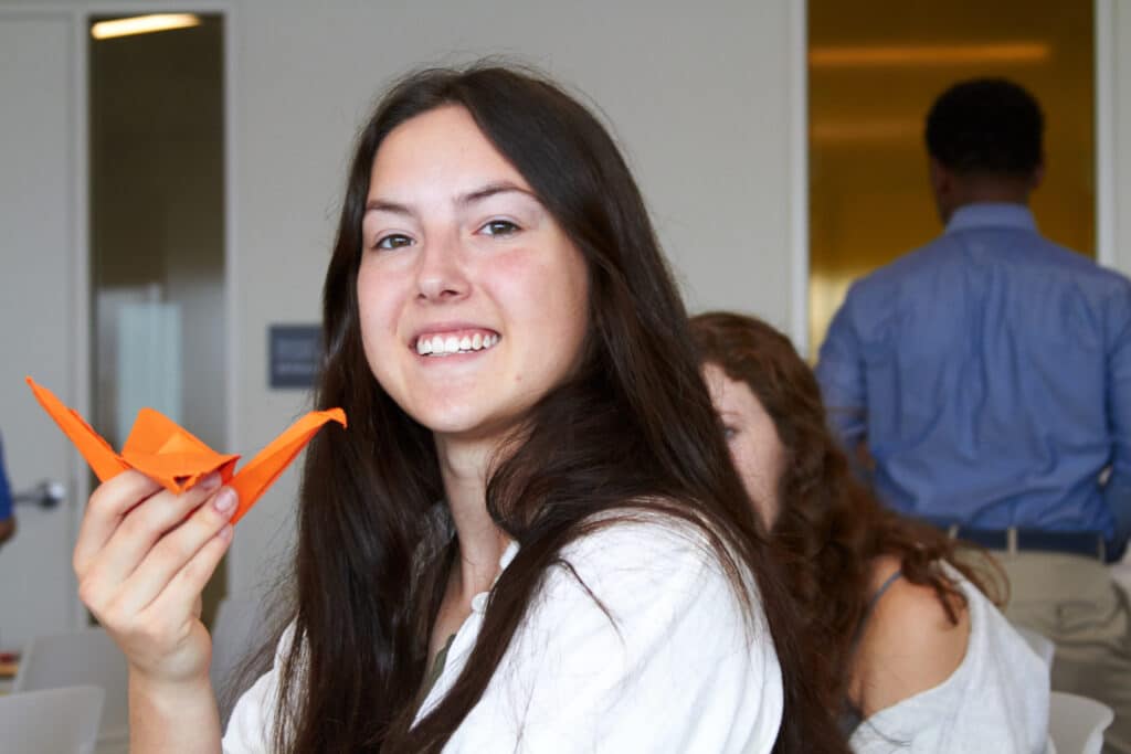 Smiling student shows off origami she created during summer immersion event.