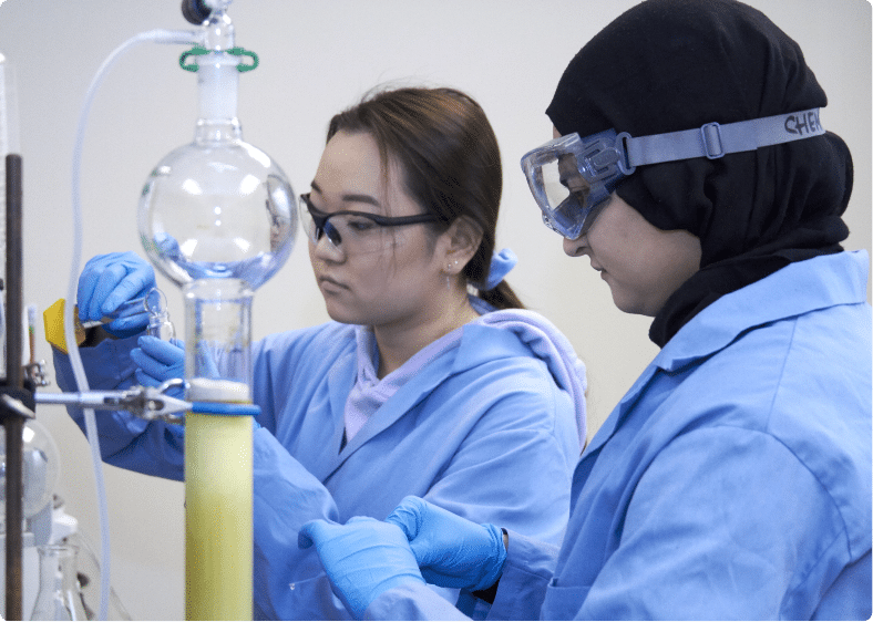 Two students wearing protective glasses engaging in research