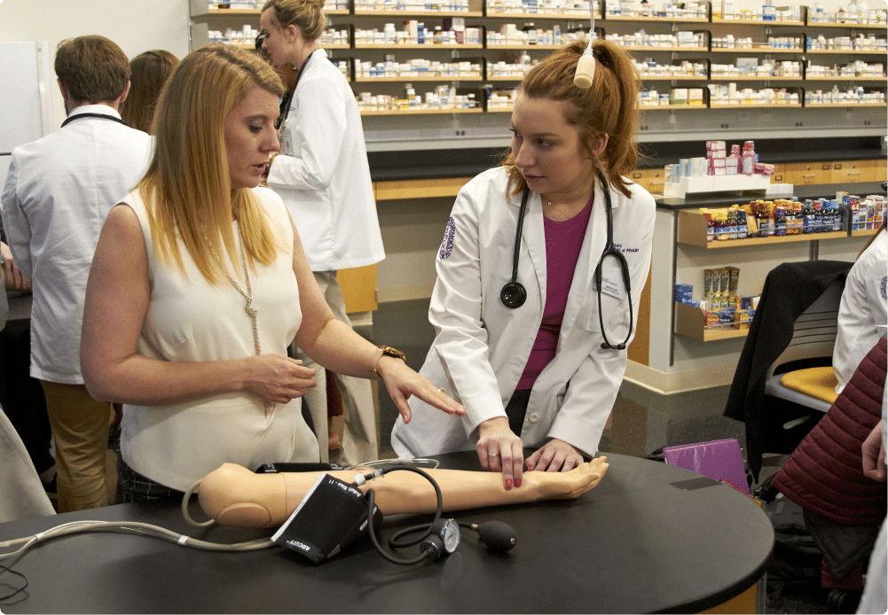 Pharmacy faculty instructs student on how to check pulse