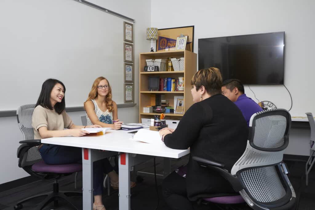 Group of students sit at table with success staff