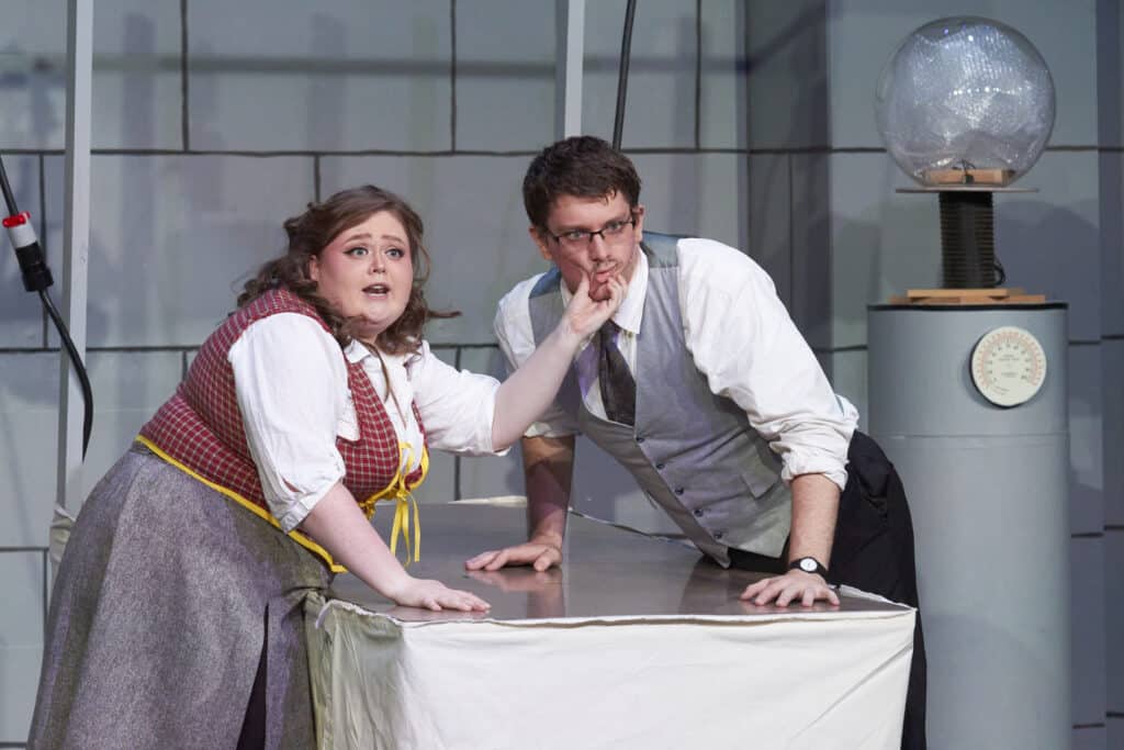 Female student grabs the face of a male student while performing during production of Young Frankenstein