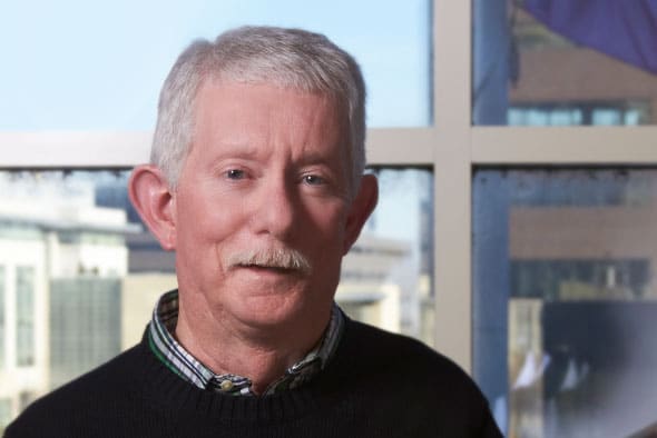 Alumnus Neil Schmidt in front of windows in Jones Hall overlooking campus.