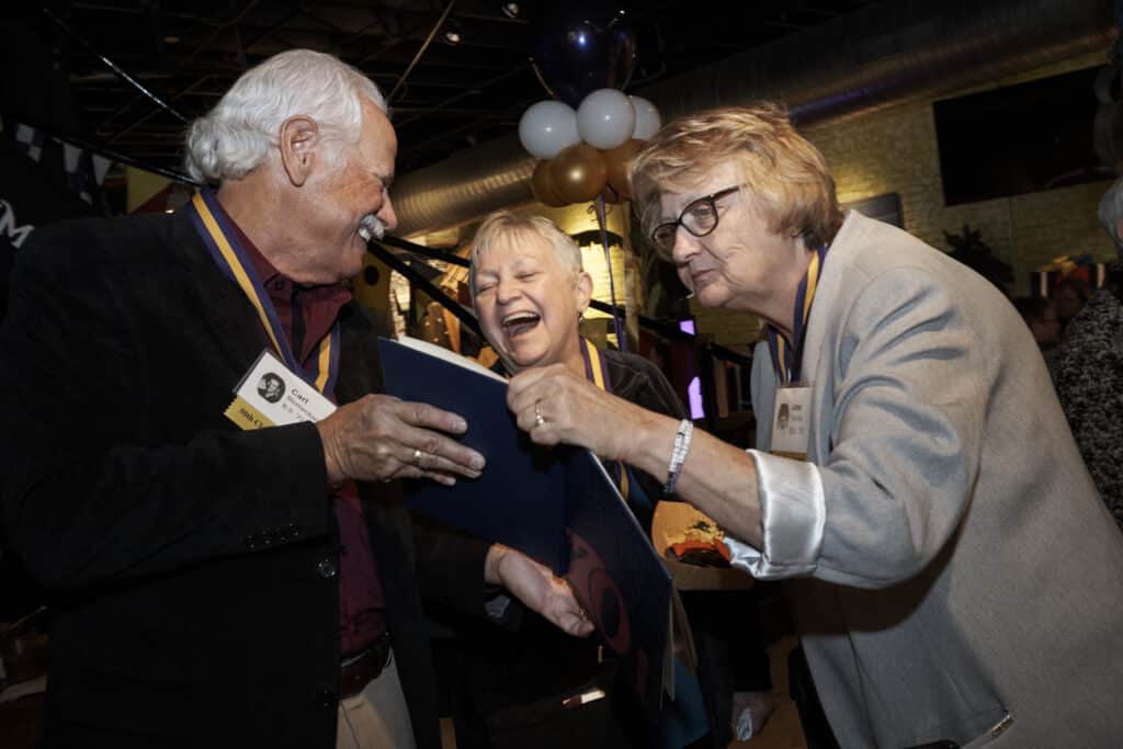 Group of alumni look at a yearbook during their UHSP reunion celebration.