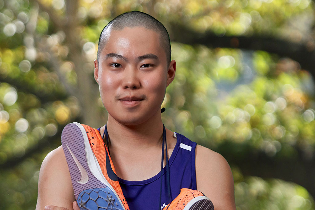 UHSP athlete Enzo Hao smiles into camera with tennis shoes around his neck