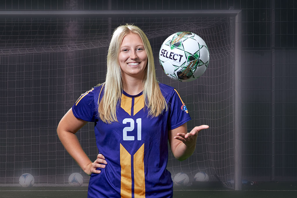 UHSP student and soccer athlete Emily Sitkowski smiles at camera while tossing a soccer ball in the air