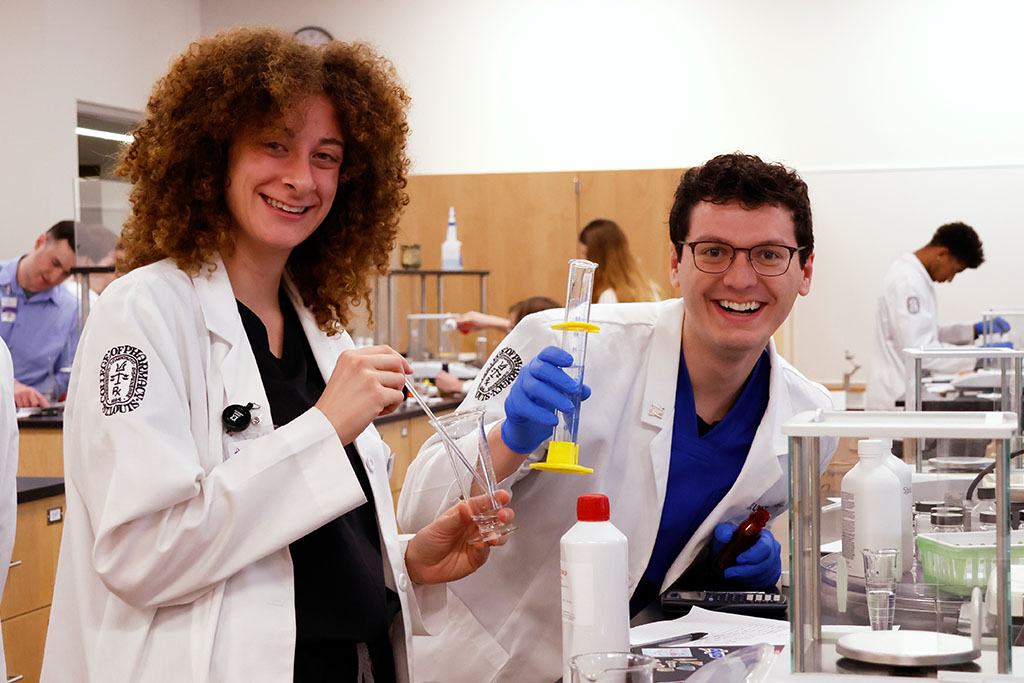 Students smiling for a photo while doing a lab.