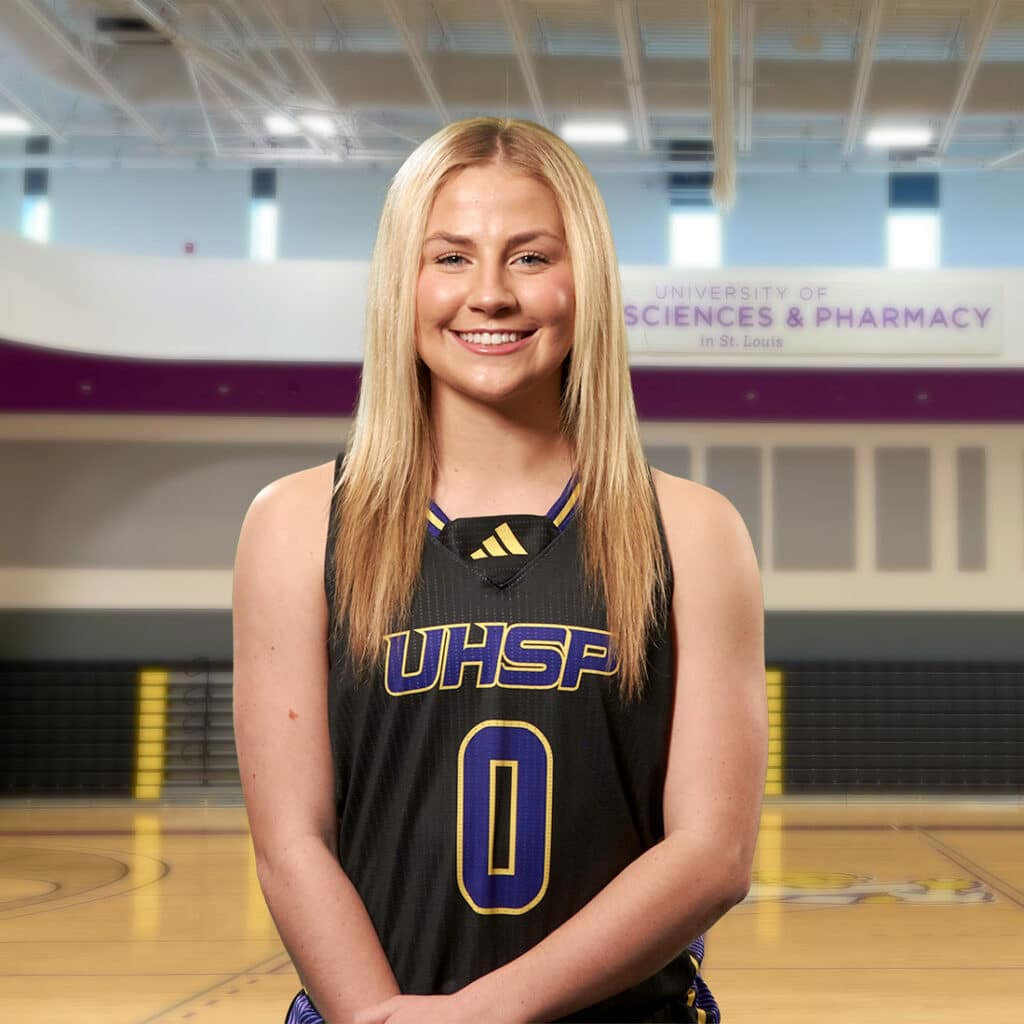 UHSP student-athlete Alivia Simily smiles in her jersey while standing in the competition gym