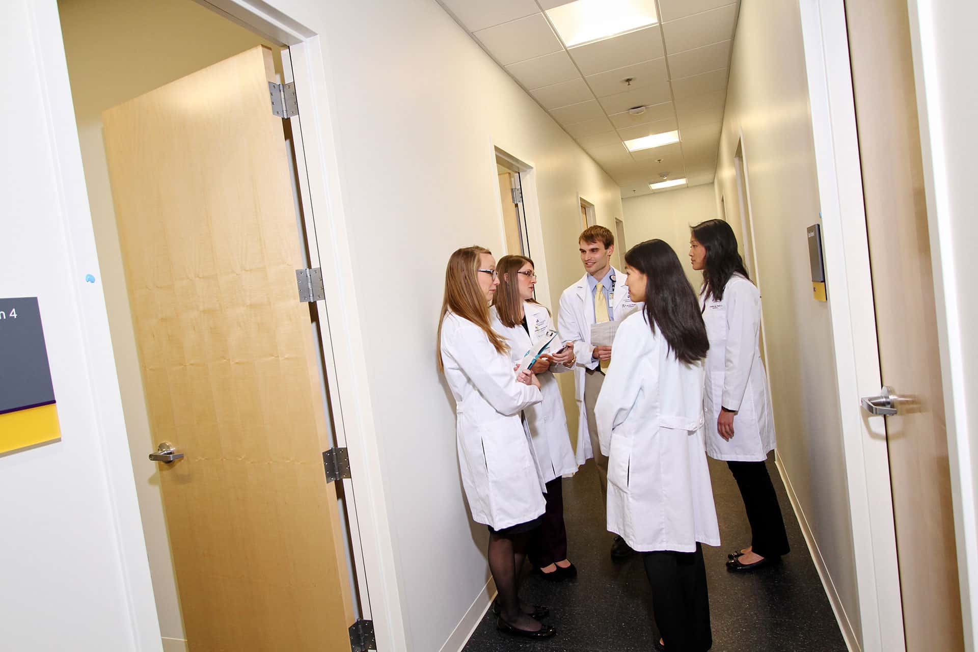group of student pharmacists conversing in exam room hallway